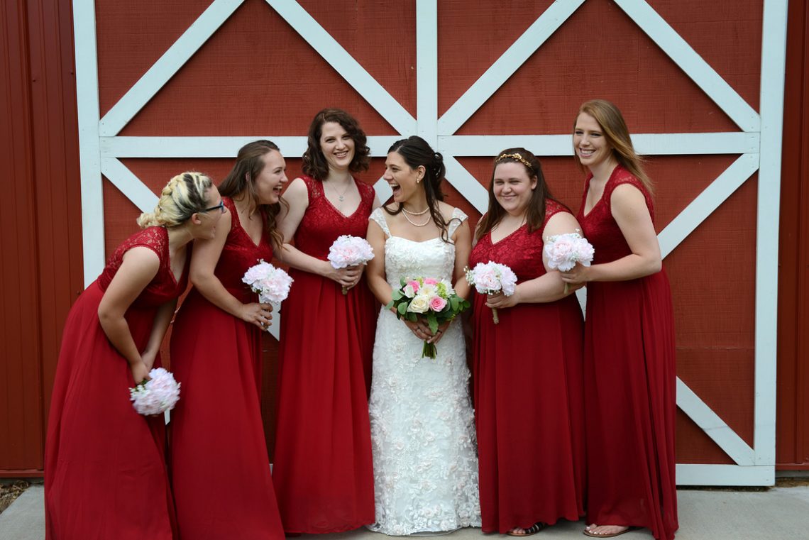 Weddings S&T Shira having fun with bridesmaids in front of red barn door